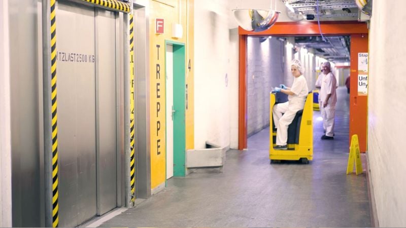 A worker using a manual truck in a food production environment