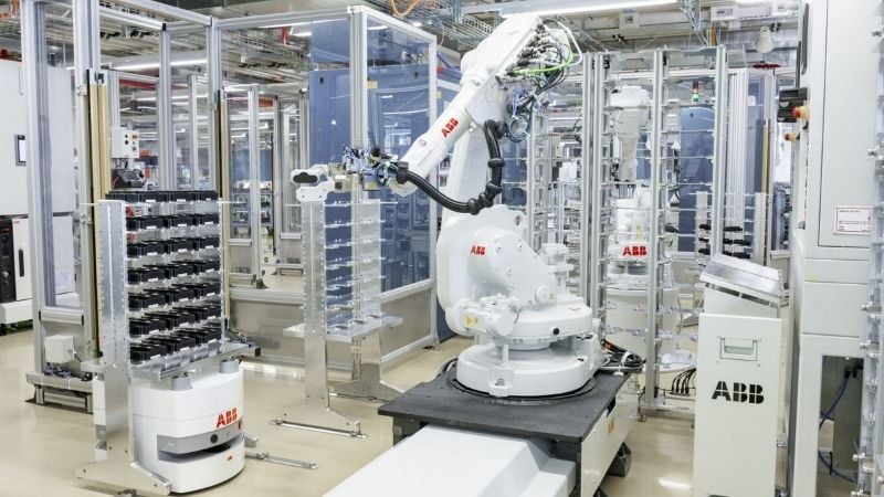 BlueBotics mini AMR working with a robotic arm in a factory.
