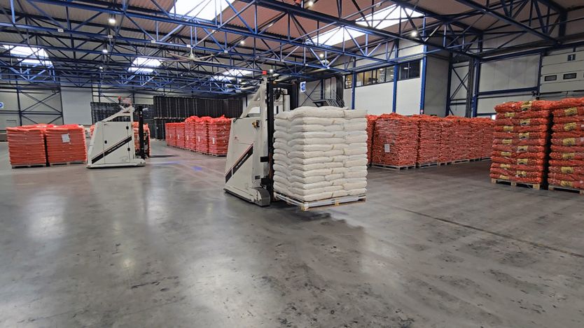 Two forklifts working together in a warehouse